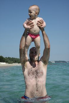 Father playing with  his baby daughter  in the sea water