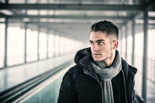 Profile view of handsome young man outdoor in winter wearing scarf, looking away thinking