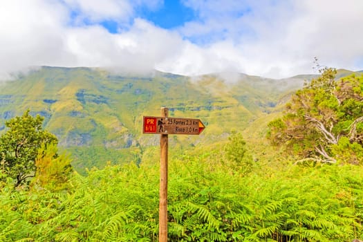 Signpost showing the way to 25 Fontes and Risco, famous walk trail for hikers on Madeira with the magnificent inland of the island of Madeira in the background