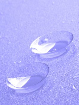 Two Contact Lenses with Water Droplets isolated on Lilac background