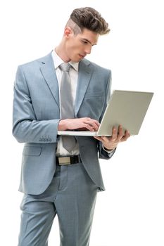 Young businessman standing and working at laptop. White background.