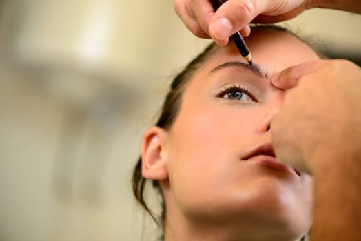 A pretty woman having eyebrow make-up applied by a makeup artist. Close up.