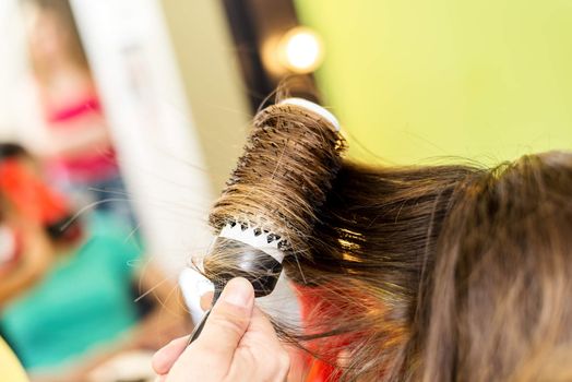 Close up of a drying long brown hair with round brush. 