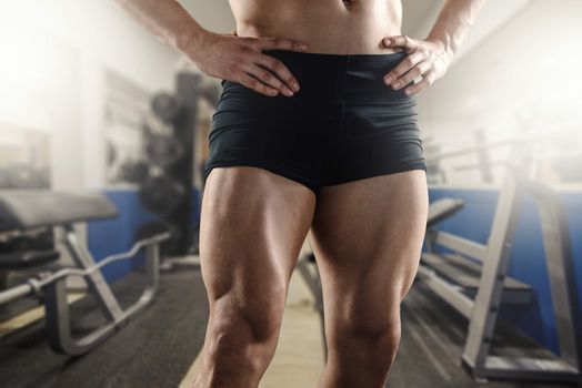 Close up of strong muscular men`s legs in the gym.