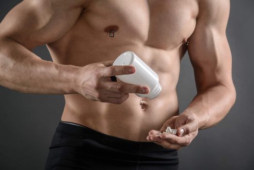 Close up of a body builder taking supplement pills