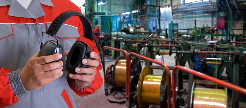 Worker with protective headphone at man hands at industrial factory