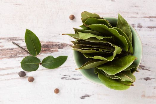Bay leaves on white wooden textured background. Culinary herb, cooking ingredient and medical herb. 