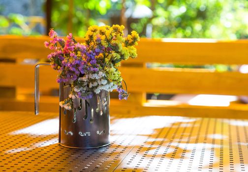 Bunch of dry flowers in a cup, standing on a table in the summer. The cup depicted notes.