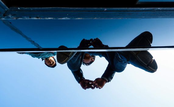 KATHMANDU, NEPAL - NOVEMBER 18, 2015: Two men travel on a bus roof. For roughly two months Nepal has been facing fuel shortage, as a result people are once again allowed to travel on bus roofs.