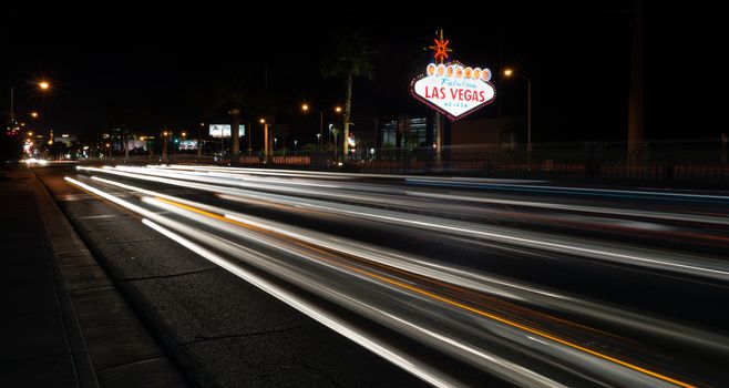 Trucks and Cars whiz by the sign welcoming all to Las Vegas
