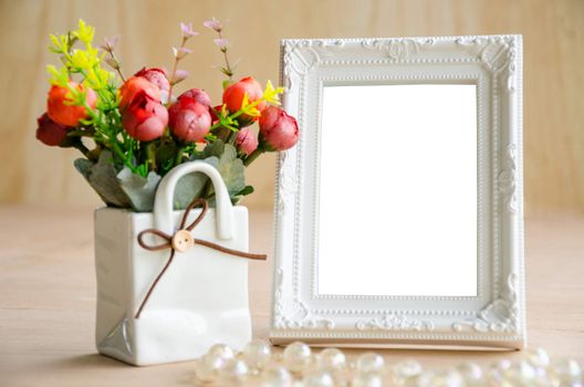 Flowers vase and vintage white picture frame on wooden desktop, clipping path