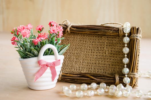 pink flower and blank photo frame made from sac on wooden background.