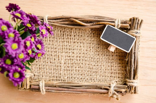 Sack photo frame, blank tag and violet fower on wooden background.