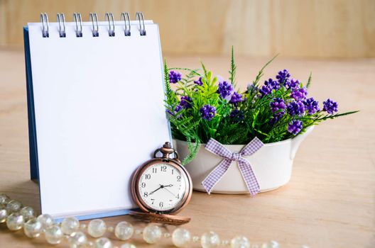 Open blank diary for your text and pocket watch with violet flower on wooden background.