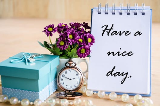 Have a nice day. Open diary, pocket watch, gift box and flower on wooden backgroudn.