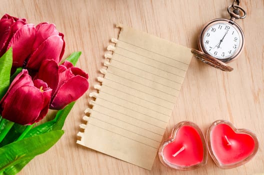 Bunch of red tulips and an paper diary made from recycle paper on wooden background.