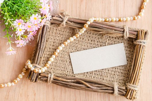 Blank Tag on sack photo frame with flower on wooden background.