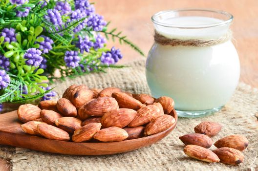 Almond milk with violet flower on sack background.