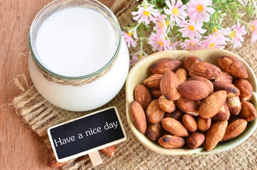 Have a nice day with almond and almond milk on sack background.