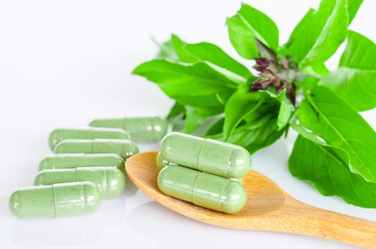 Green Herb capsule medicine and green leaf on white background.