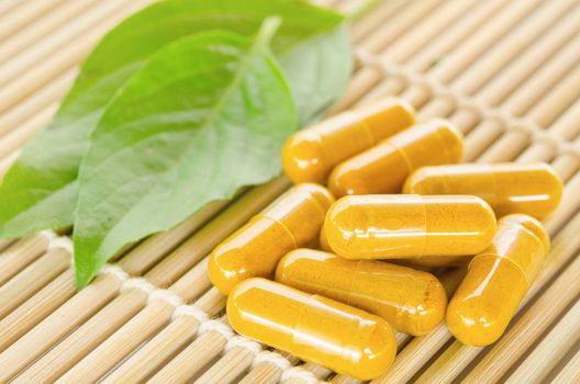 Yellow herbal medicine on wooden mat with leaf.