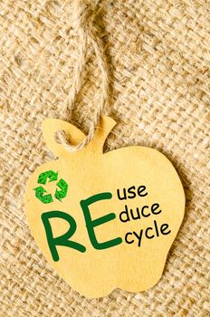 Recycle sign and Reduce, Reuse, Recycle wording on paper recycle apple shape tag on sack background. Recycle paper concept.