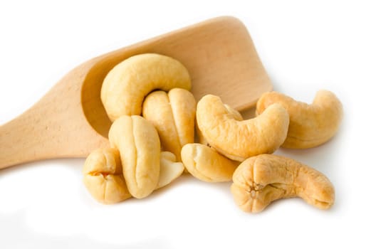 Roasted cashew nuts in wooden spoon on white background.
