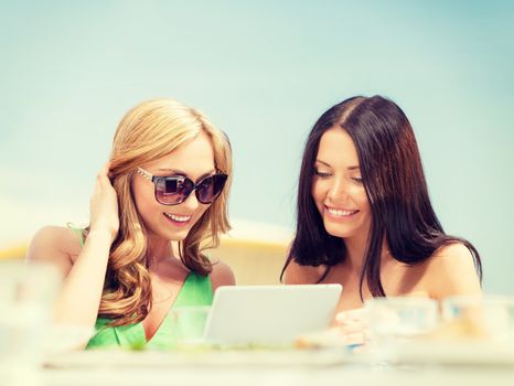 summer holidays, vacation, internet and technology concept - smiling girls looking at tablet pc in cafe