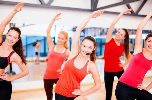 fitness, sport, training, gym and lifestyle concept - group of smiling people stretching in the gym