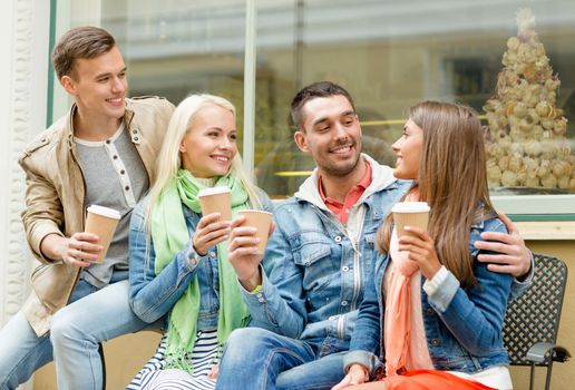 friendship, travel, drink and vacation concept - group of smiling friends with take away coffee