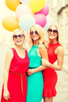 holidays and tourism, friends, hen party, blonde girls concept - three beautiful women with colorful balloons in the city