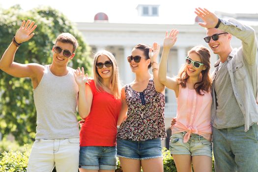 friendship, leisure, summer, gesture and people concept - group of smiling friends waving hands outdoors