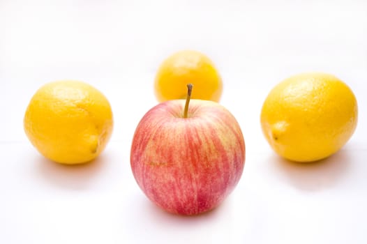 Fruits conceptual image. Apple among lemons on isolated background.