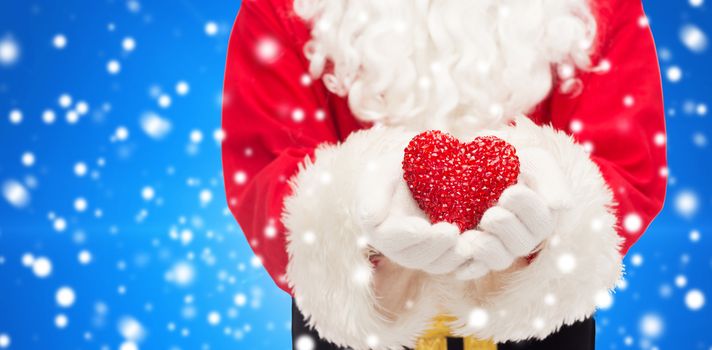 christmas, holidays, love, charity and people concept - close up of santa claus with heart shape decoration over blue snowy background