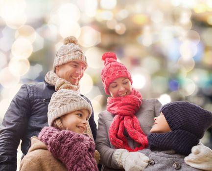 family, childhood, season, holidays and people concept - happy family in winter clothes over lights background