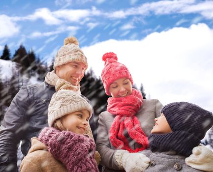 family, childhood, season and people concept - happy family in winter clothes over snowy mountains background