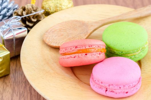 Colorful macaroons in wooden dish and decoration christmas on wooden background.