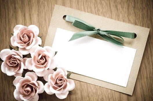 Vintage greeting card and rose flower on wooden background.