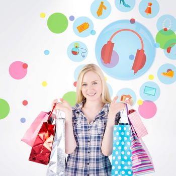 Pretty young blonde holding shopping bags against dot pattern