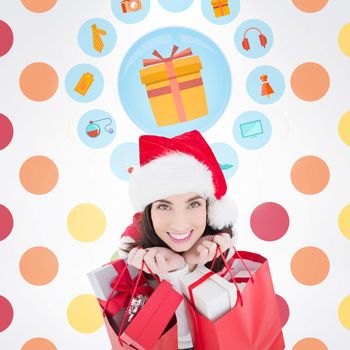 Smiling brunette holding shopping bags full of gifts  against colorful polka dot pattern 