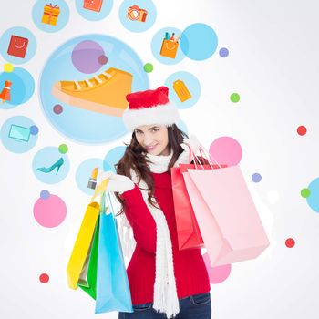 Smiling brunette in winter wear holding shopping bags against dot pattern