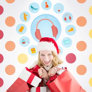 Girl in winter fashion holding presents and shopping bags against colorful polka dot pattern 