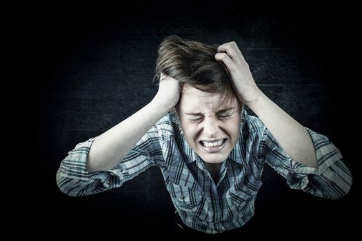 Pretty brunette shouting with hands on head against black background