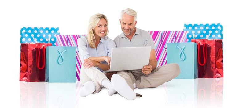 Cheerful couple using laptop against white background with vignette