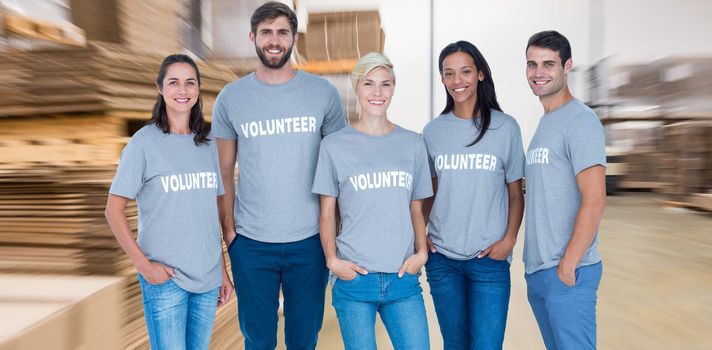 Volunteers friends smiling at the camera against  cardboard boxes in warehouse