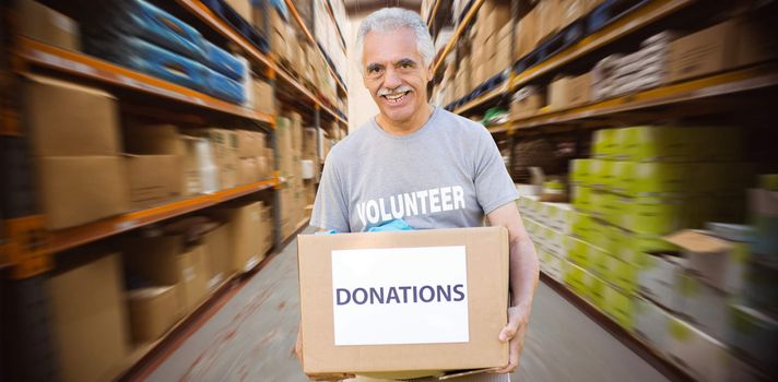 Happy volunteer senior holding donation box against worker with trolley of boxes
