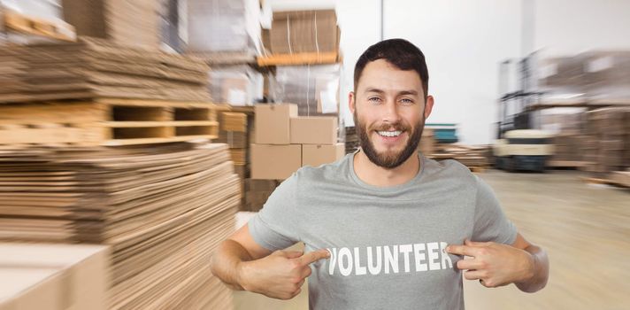 Man showing volunteer text on tshirt  against  cardboard boxes in warehouse