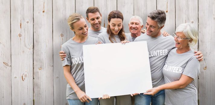 Happy volunteer family holding a blank  against wooden background