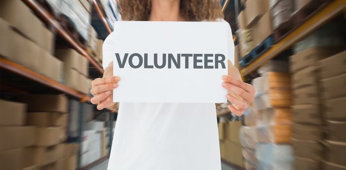 Volunteer showing a poster against shelves with boxes in warehouse