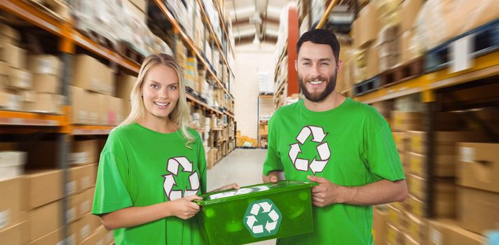 Portrait of smiling volunteers carrying recycling container  against shelves with boxes in warehouse